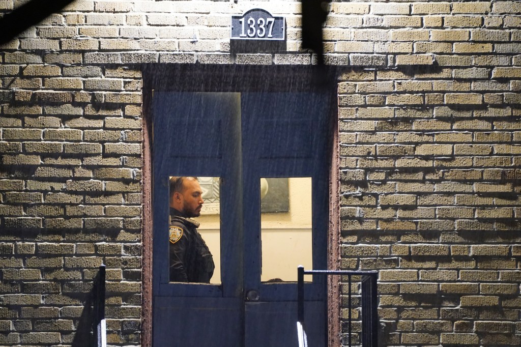 A police officer standing at the door of 1337 Beach Avenue in the Bronx.