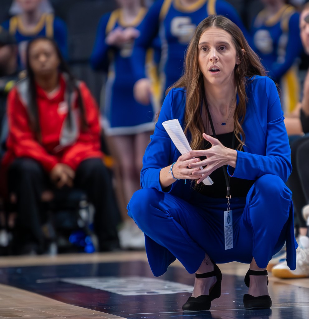 Paige Adams, a high school basketball coach, crouching on the sidelines.