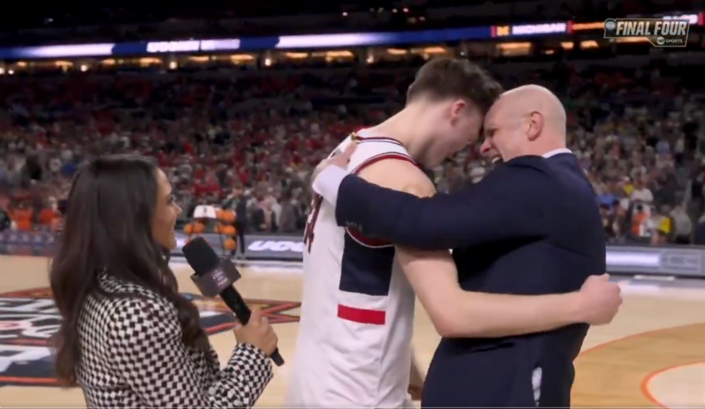 A basketball player and coach embrace on the court during an interview, with a "FINAL FOUR" logo visible in the background.