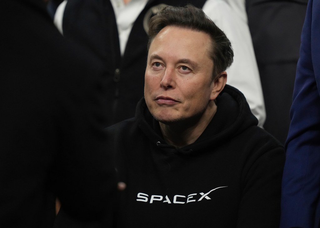 Elon Musk in a black "SpaceX" hoodie.