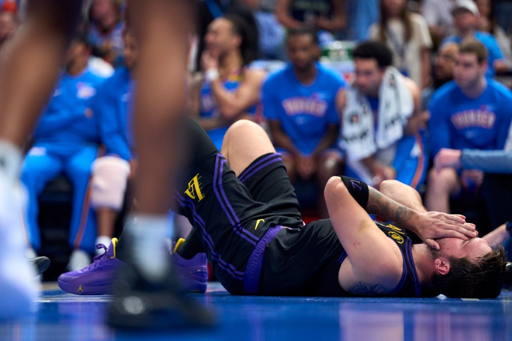 Luka Doncic #77 of the Los Angeles Lakers lies on the floor covering his face after a play.