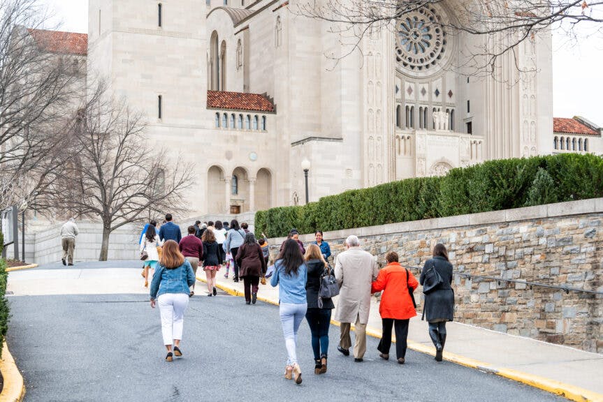 Washington DC, USA - April 1, 2018: Many people walking by the basilica of the National Shrine of the Immaculate Conception Catholic church street road on Easter