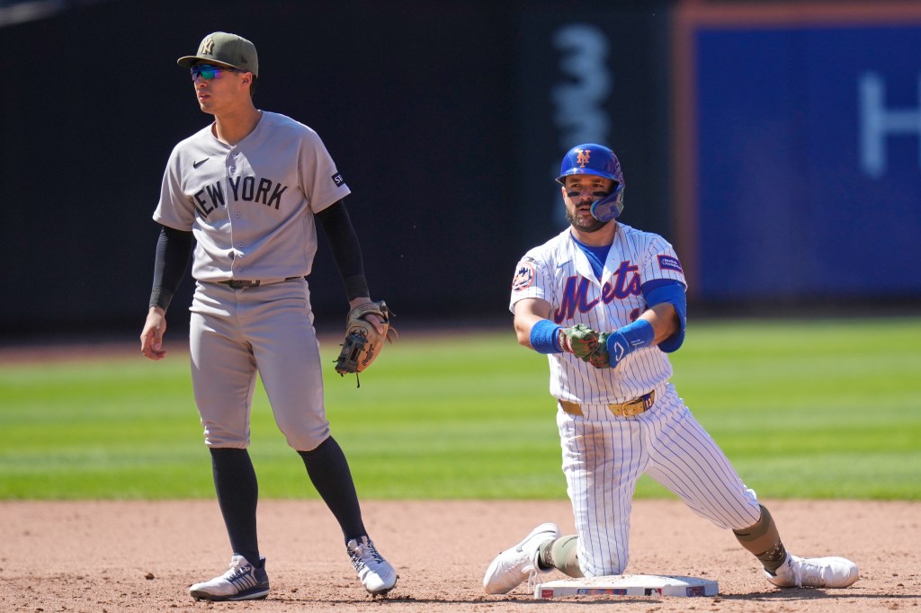 New York Yankees shortstop Anthony Volpe and New York Mets' Luis Torrens on the baseball field.