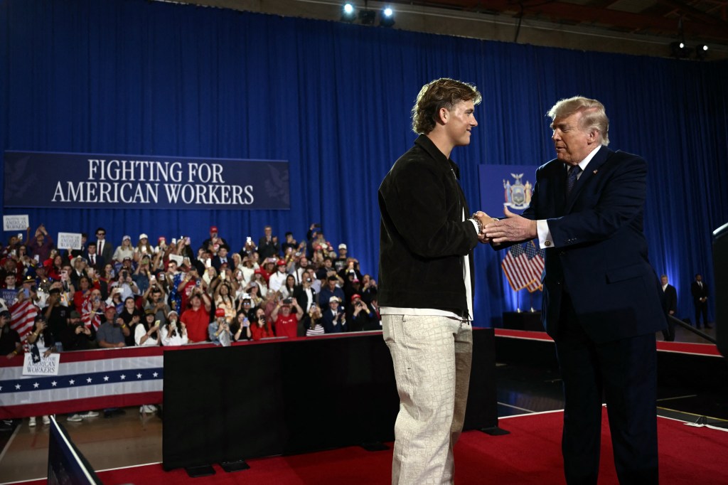 Donald Trump shaking hands with Jaxson Dart at an economic speech.