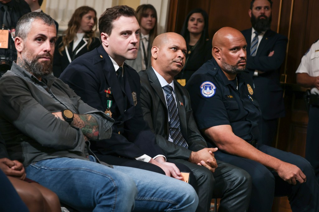 Four police officers, three seated and one standing, attend a hearing of the January 6th Committee.