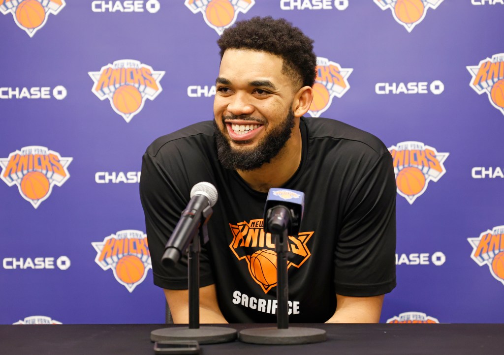 Karl-Anthony Towns smiling at a press conference with two microphones in front of him.